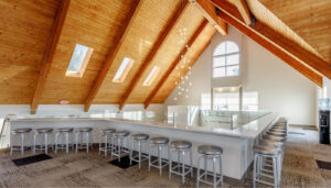 clubhouse with wooden ceilings, chandelier and bar top with bar stools.